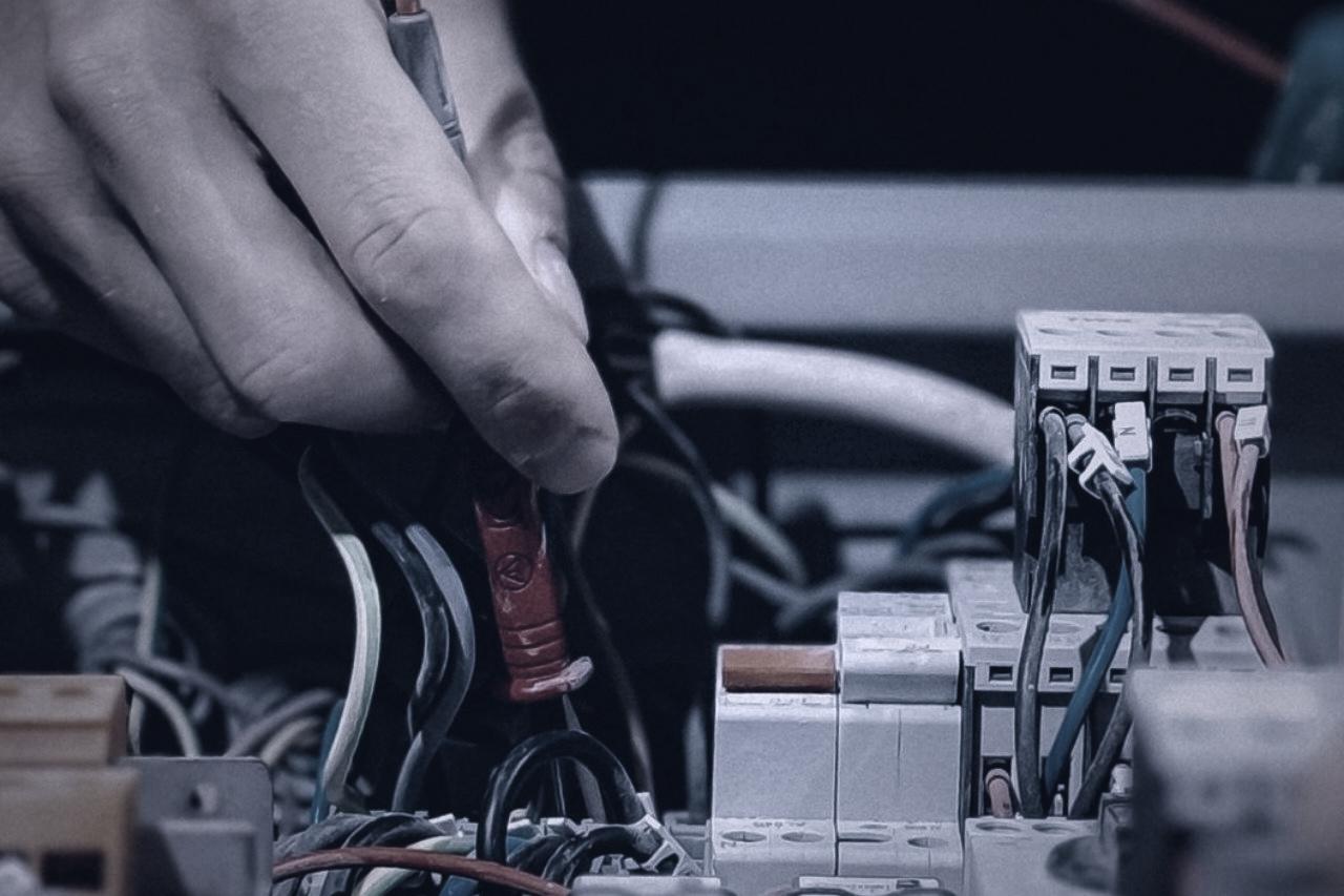 An engineer testing a distribution board with a multimeter probe